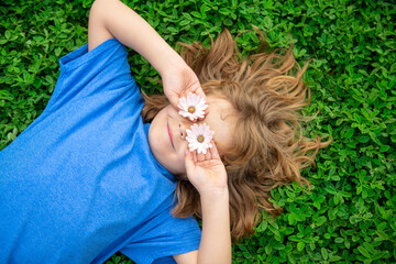 Kids having fun in spring park. Child lying on green grass. Top view portrait.