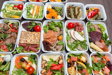 Fototapeta na wymiar Airplane food presentation with variety of in flight meals. Flight catering. Food on airplanes. Salad bar buffet display in restaurant. Meat cuts. Hot appetizers. Close-up, a lot of food. 