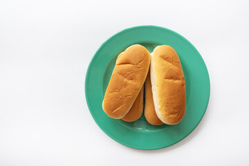 Fresh hot dog buns which lie on a green plate. View from above.