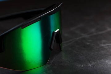 Green sports glasses with a mirror lens on a dark background