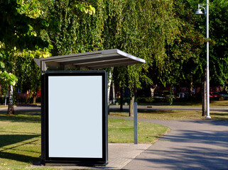 image composite of bus shelter and bus stop. blank light box. glass structure. park like urban...