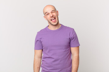 bald man with cheerful, carefree, rebellious attitude, joking and sticking tongue out, having fun