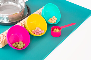 Animal food supplements concept. Bowl and spoon full of tablets, pills, softgel, capsule, treats. Dietary supplements for cats. Vitamins for cats and dogs. Prevention medicines for animals.
