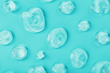 Drops of Gel with hyaluronic acid in the form of a smear of glossy texture on a cyan background.