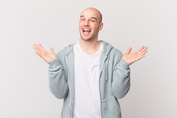 bald man feeling happy, excited, surprised or shocked, smiling and astonished at something...