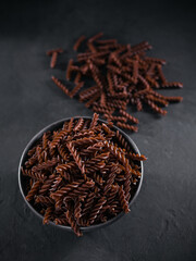 Organic uncooked Buckwheat Fusilli pasta on dark background. Wholegrain gluten free noodles. Healthy food concept.