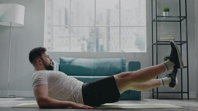 Muscular athlete with beard practices flutter kicks exercise