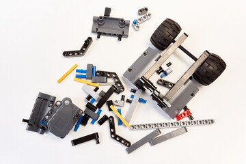 Plastic parts of the constructor, connecting elements and wheels for assembling movable models on a white background, floating focus.