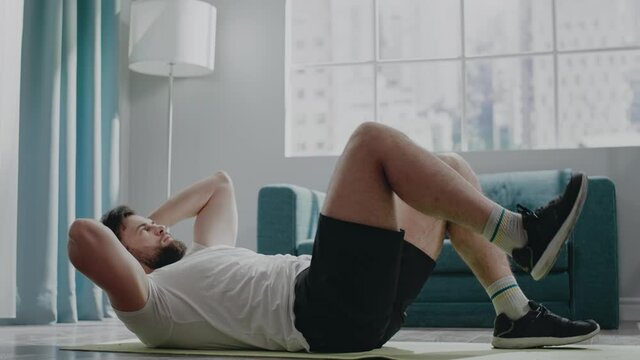 Muscular businessman practices bicycle crunches at home