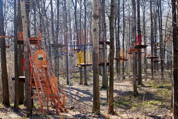 Fototapeta na wymiar Rope park in the spring forest. Wooden platforms on trees.