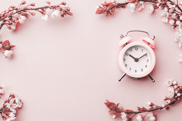 Spring background table. May flowers and April floral nature with alarm clock on pink. For banner,...