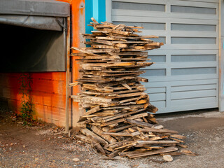 Various Sized Timbers Stacked Outside an Orange Garage