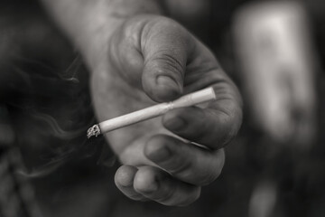 Background Hand of a man, a smoker, holding a cigarette black and white, monochrome photo. The "No smoking" concept. Bad habit, dependence on smoking, which has a dangerous effect on the human body