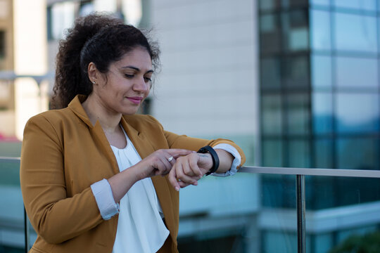 Young fashionable woman using smartwatch and checking notifications outdoors