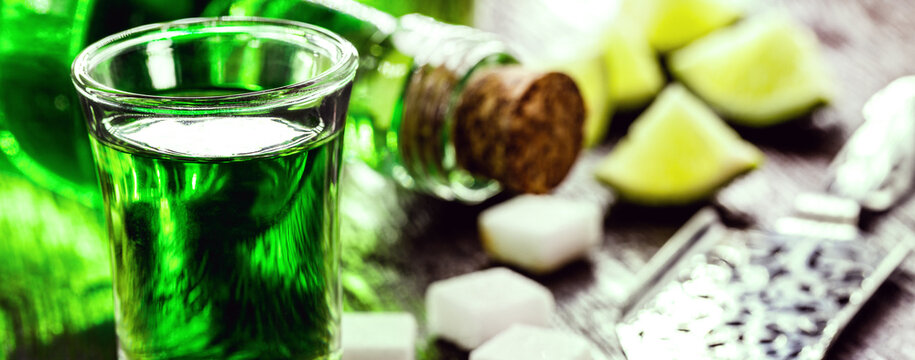 doses of absinthe with sugar cubes. Absinthe bottle, green distilled drink