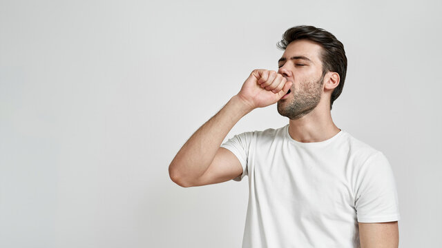 Bored and sleepy young bearded man yawning