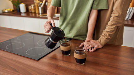 Young same sex male pair pouring coffee into cups