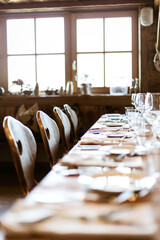 Gedeckter Tisch mit Stühlen, Tellern, Gläsern und Dekoration am Fenster