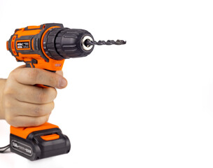Electric drill with a drill bit in hand. A screwdriver on the battery. Isolated on a white background, close-up, selective focus.