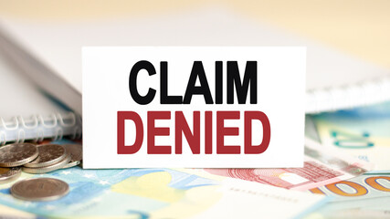 On the table are banknotes, coins and a sign that says - claim denied. Financial and economic...