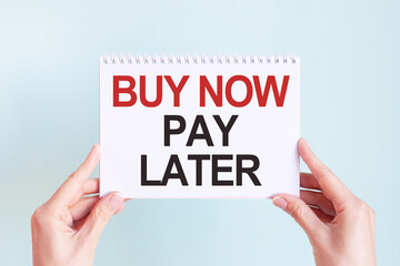 buy now pay later word inscription on white card paper sheet in hands of a woman. Business concept