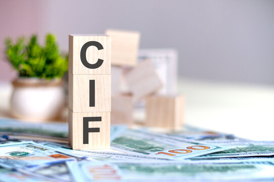wooden cubes with the letters cif arranged in a vertical pyramid on banknotes, business concept