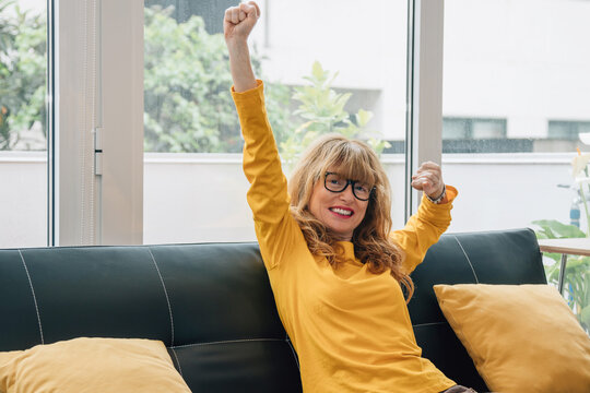 cheerful woman celebrating success on the sofa at home