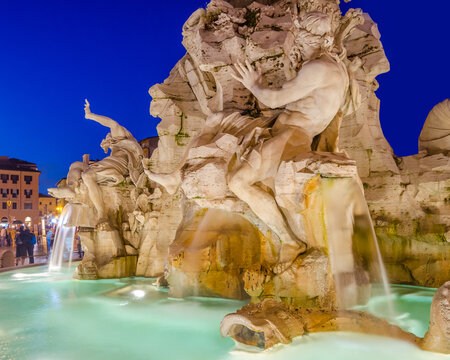 Illuminated at night the fontana del Moro (the Moor Fountain) on Piazza Navona on the Sant'Agnese in Agone church background, Rome, Italy