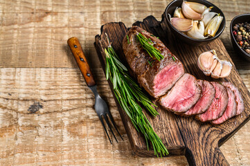 Grilled sliced lamb fillet meat steak on a cutting board. wooden background. Top view. Copy space