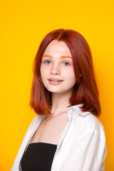 Fototapeta premium Redhead girl on a yellow background. Large portrait
