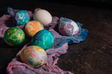 multi-colored Easter eggs of blue tones on a multi-colored cloth background. Easter eggs in low key
