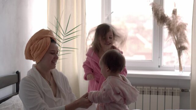happy united family applaud health workers, doctors and heroes in fight against coronavirus pandemic. mom and kids in bathrobes after bath on bed oposite window. Celebration quarantine ending concept