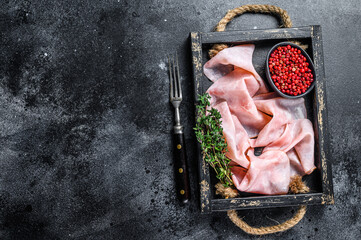 Thin sliced Smoked  pork ham in wooden tray. Black background. Top view. Copy space