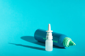 Bottles with nasal spray on a blue background, place for text. Rinsing and treatment of the common cold. Protection from viral diseases.