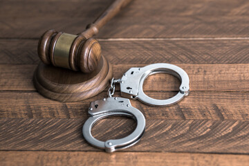 handcuffs with judge gavel on table