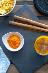 golden milk with cinnamon in a glass tumbler with cinnamon sticks and a bowl of turmeric a healthy drink for immunity virus control