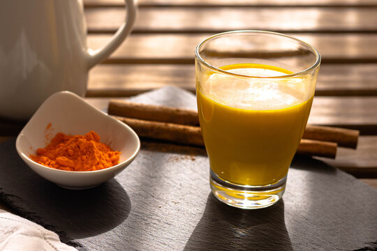 Golden milk of turmeric and cinnamon that is a source of health and vivacity traditional Indian healthy detox with light from the window.