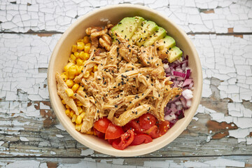 Aerial view of an avocado chicken poke and cherry tomatoes.
