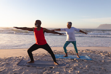 Senior african american couple performing stretching exercise together at the beach