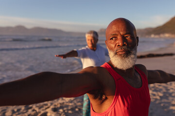 Senior african american couple performing stretching exercise together at the beach