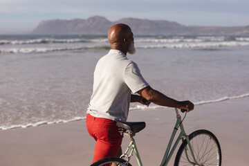 Senior african american man with bicycle walking together on the beach