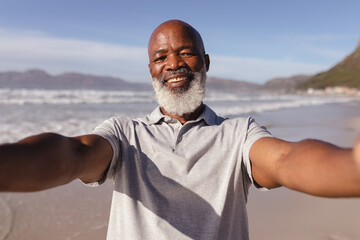 Portrait of african american man taking a selfie on the beach - Powered by Adobe