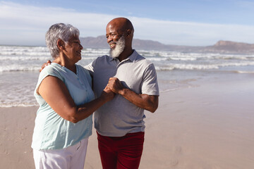 Happy senior african american couple embracing each other on the beach
