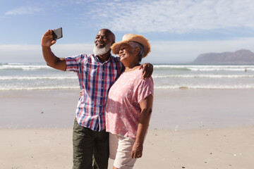 Happy senior african american couple taking a selfie from smartphone on the beach