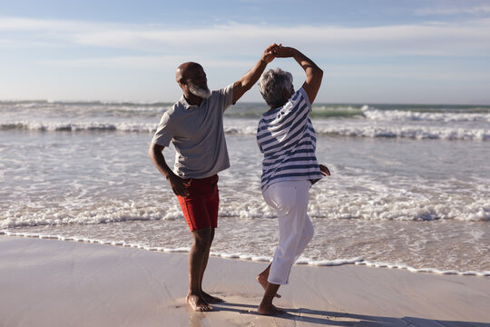 Happy senior african american couple dancing together on the beach
