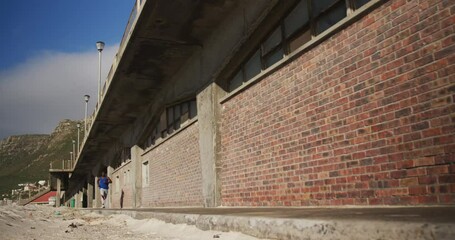 African american man running on pavement, exercising outdoors on sunny day