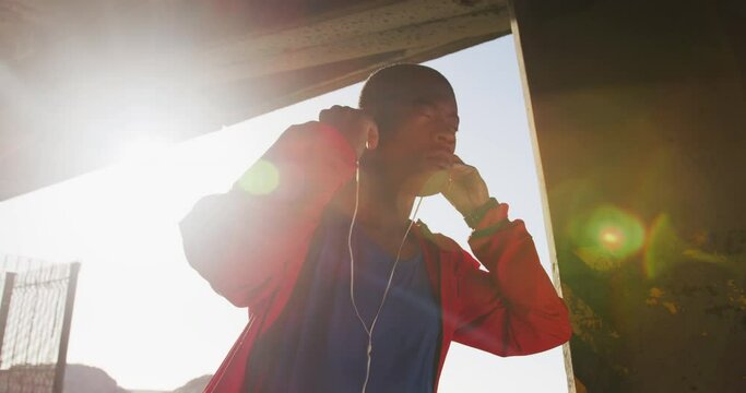 Focused african american man putting earphones on before exercising outdoors by the sea