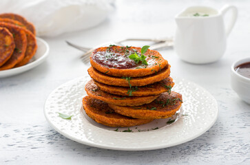 Lentil fritters with plum sauce, tkemali and yoghurt sauce, greens in white plate on light blue textured background. Healthy vegan food