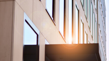 Blue sky reflection in glass facade of building. View of office building windows close up with sunrise, reflection and perspective.. Glass facade on a bright sunny day with sunbeams on the blue sky. 