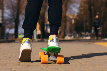 A child is riding a green skateboard or penny board in the park. The teenager is fond of...